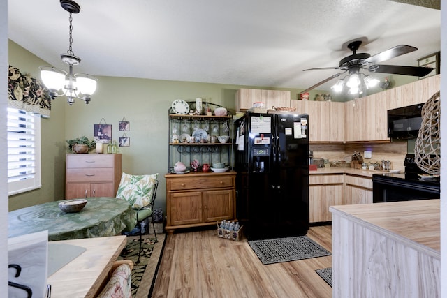 kitchen featuring wood counters, light wood-type flooring, ceiling fan with notable chandelier, black appliances, and pendant lighting