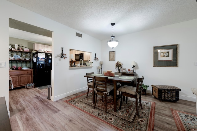 dining space featuring light wood-type flooring and a textured ceiling