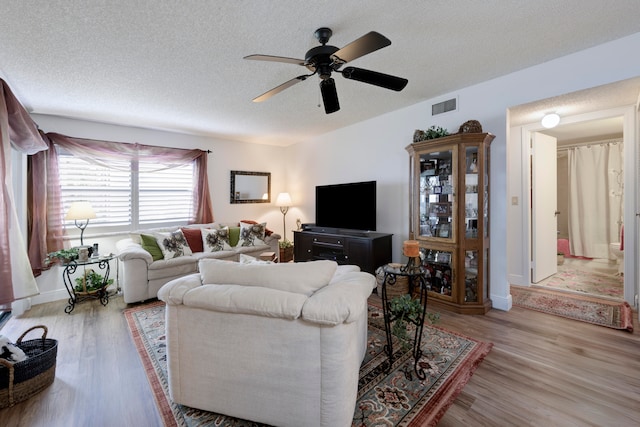 living room with a textured ceiling, light hardwood / wood-style flooring, and ceiling fan