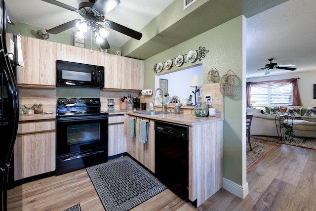 kitchen featuring black appliances, light brown cabinets, light wood-type flooring, and sink