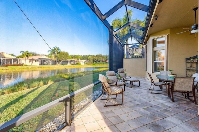 unfurnished sunroom with ceiling fan and a water view