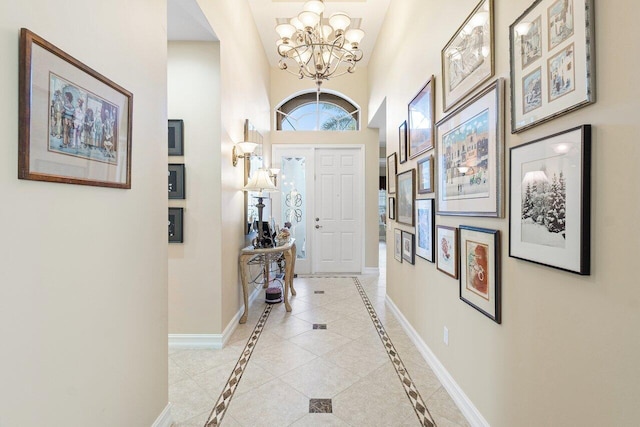 tiled entrance foyer featuring a notable chandelier and a towering ceiling