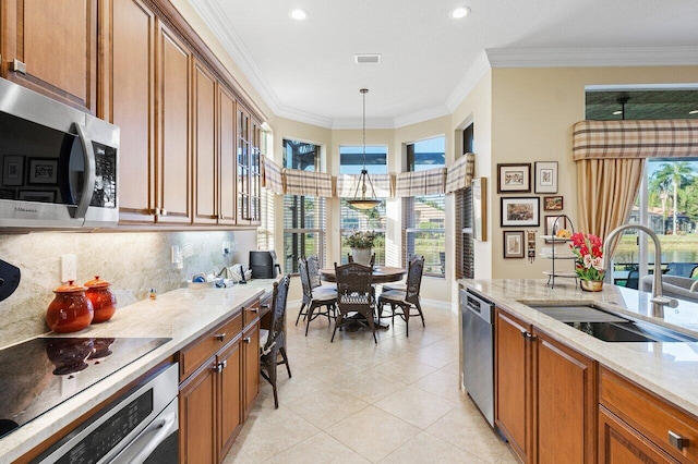 kitchen featuring sink, hanging light fixtures, stainless steel appliances, crown molding, and plenty of natural light