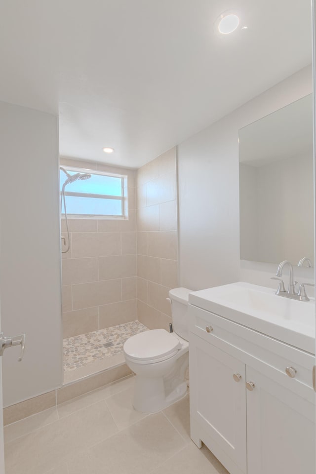 bathroom featuring tile patterned floors, vanity, toilet, and tiled shower