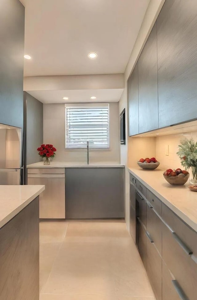 kitchen with light tile patterned floors, stainless steel refrigerator, and sink