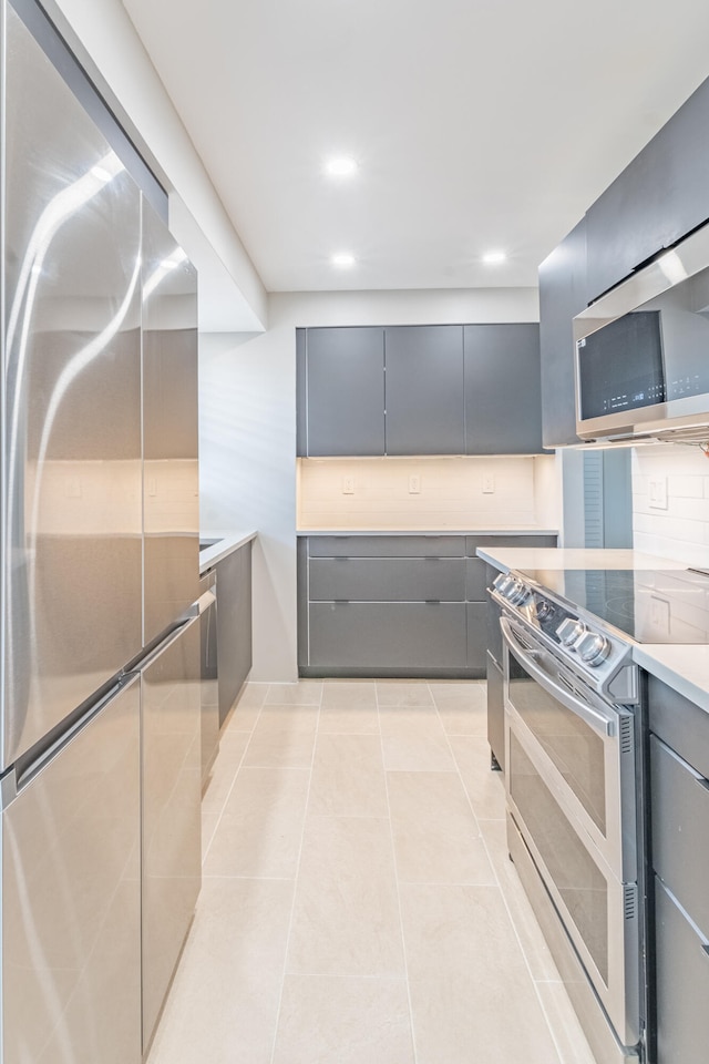 kitchen featuring backsplash, gray cabinets, light tile patterned flooring, and stainless steel appliances