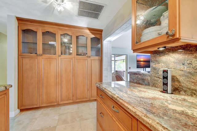 kitchen featuring light stone countertops and backsplash