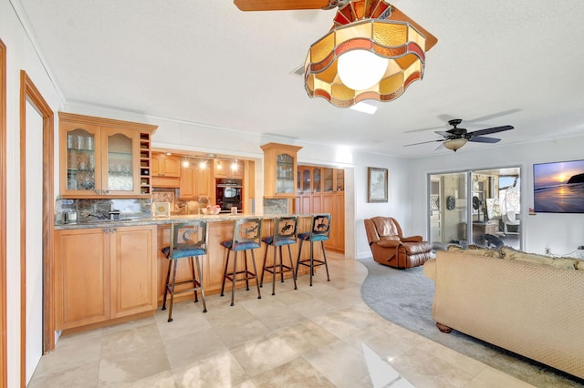 kitchen with a kitchen breakfast bar, ceiling fan, decorative backsplash, a textured ceiling, and kitchen peninsula