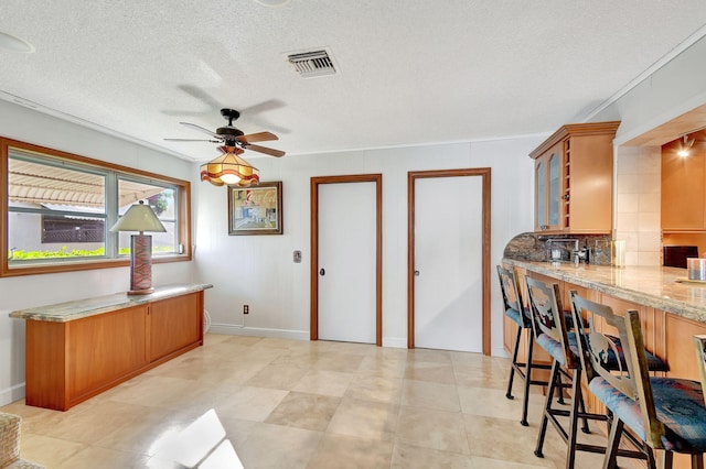 kitchen with ceiling fan, a textured ceiling, and ornamental molding