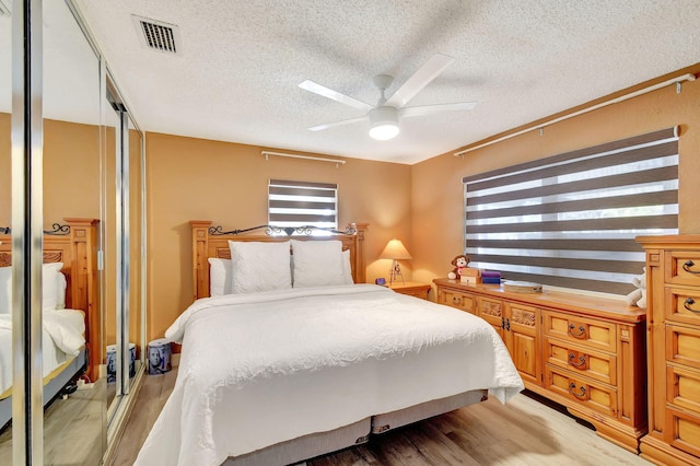 bedroom with ceiling fan, light hardwood / wood-style flooring, and a textured ceiling