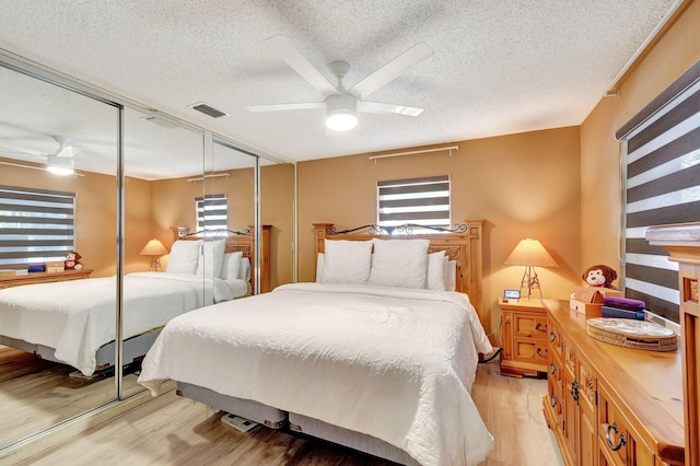 bedroom featuring ceiling fan, light hardwood / wood-style floors, multiple windows, and a closet