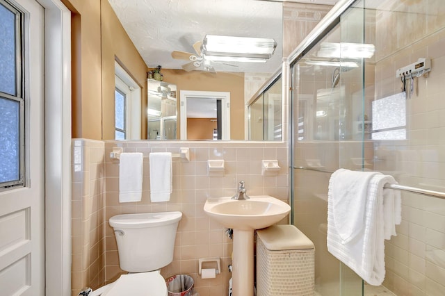 bathroom featuring a textured ceiling, toilet, tile walls, and walk in shower