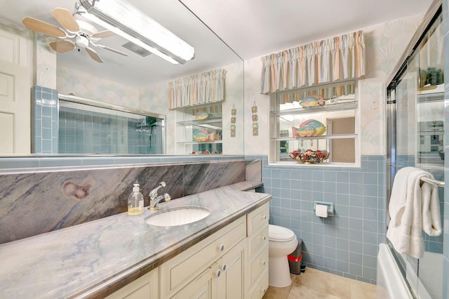 full bathroom with vanity, tile patterned flooring, ceiling fan, toilet, and tile walls