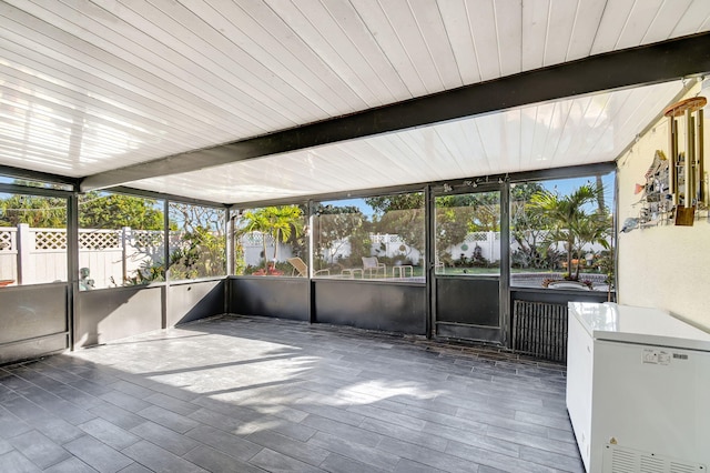 unfurnished sunroom featuring beamed ceiling