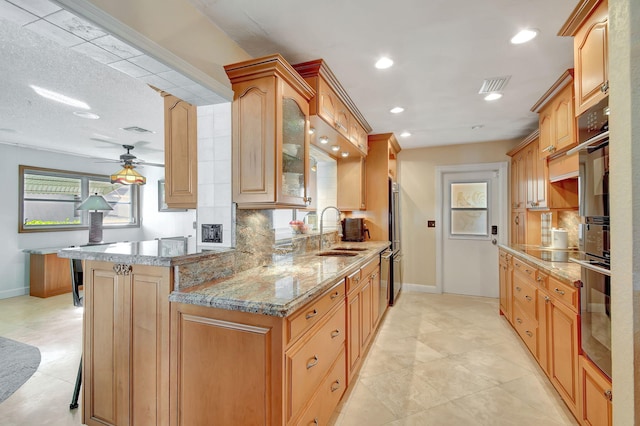 kitchen with kitchen peninsula, decorative backsplash, a breakfast bar, ceiling fan, and sink