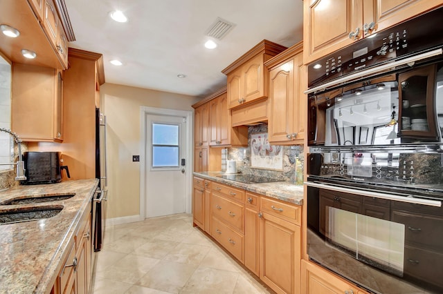 kitchen featuring sink, light stone counters, decorative backsplash, light tile patterned flooring, and black appliances