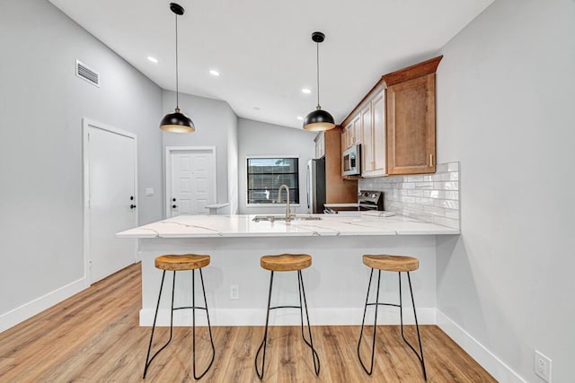 kitchen with stainless steel appliances, light hardwood / wood-style flooring, lofted ceiling, and sink