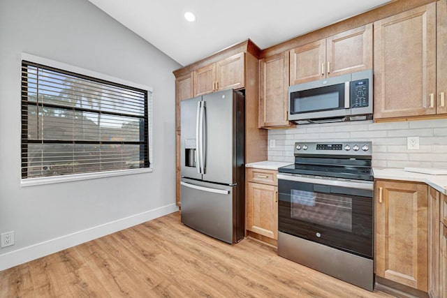 kitchen with light wood-type flooring, stainless steel appliances, tasteful backsplash, and lofted ceiling