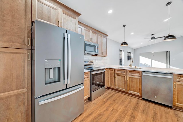 kitchen with pendant lighting, stainless steel appliances, lofted ceiling, and sink