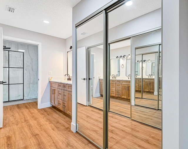 bathroom with a shower, hardwood / wood-style floors, vanity, and a textured ceiling