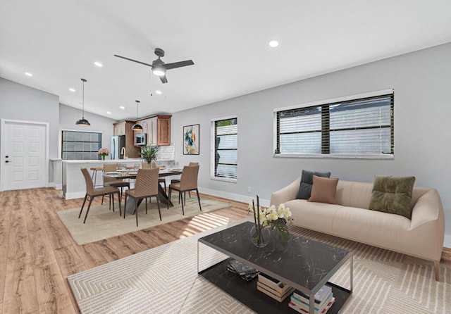 living room with light hardwood / wood-style flooring, vaulted ceiling, and ceiling fan