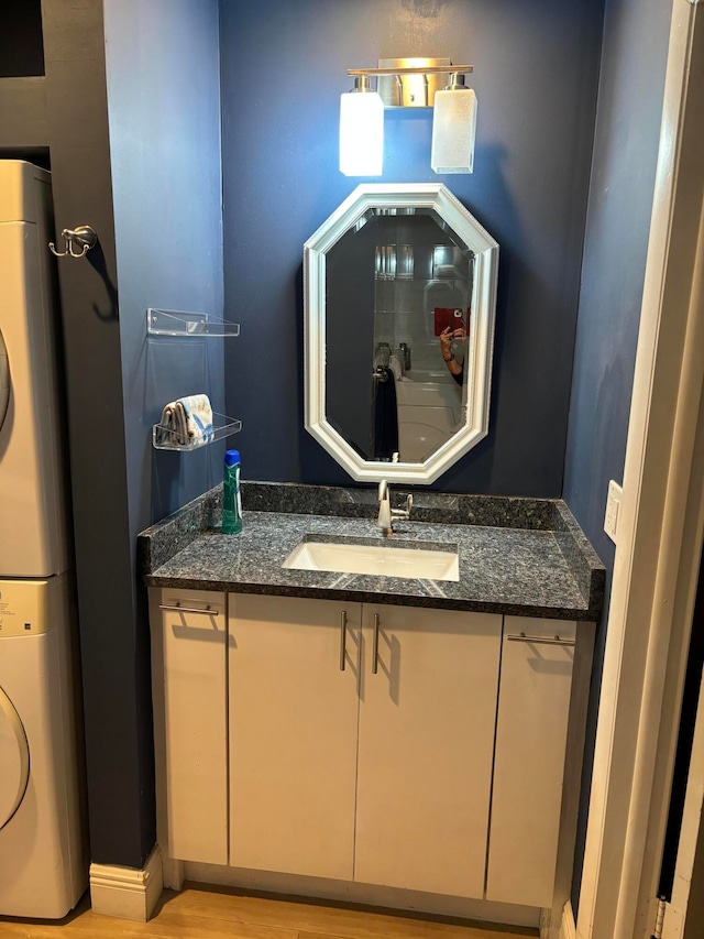 bathroom featuring hardwood / wood-style floors, vanity, and stacked washing maching and dryer