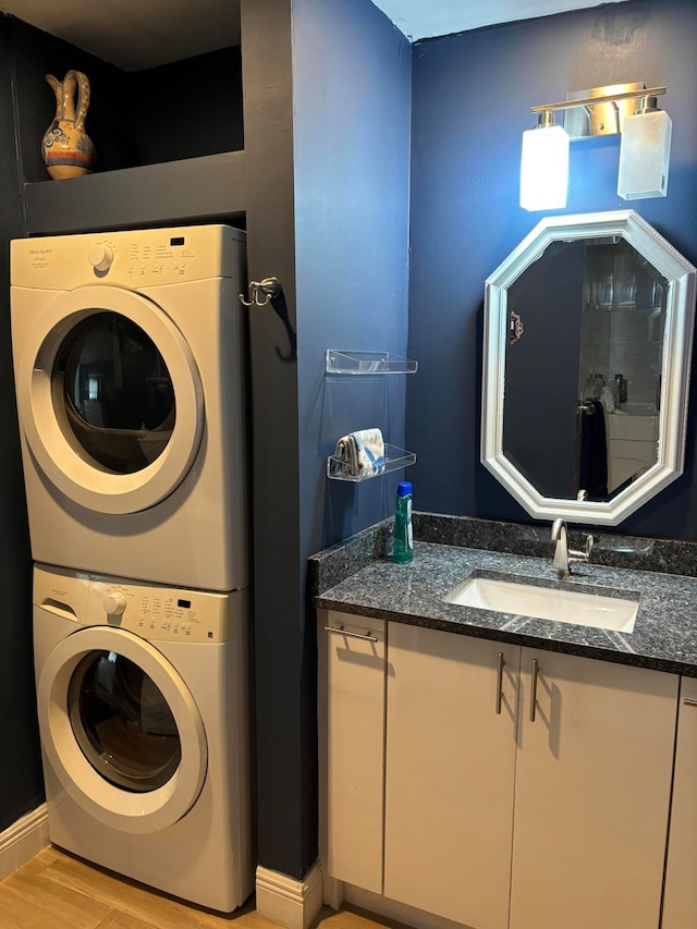 laundry area featuring light wood-type flooring, stacked washer and dryer, and sink