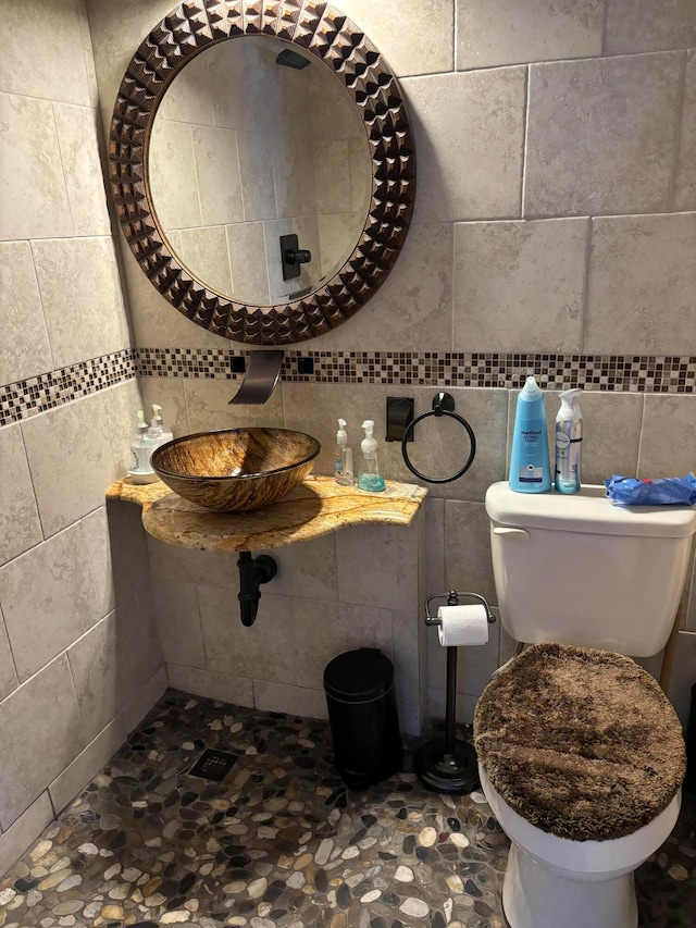 bathroom featuring sink, tile walls, and toilet