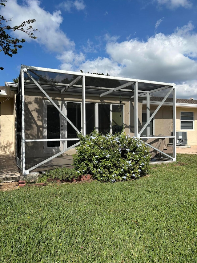 rear view of house featuring glass enclosure and a yard