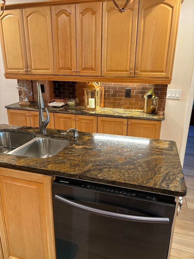 kitchen with backsplash, light hardwood / wood-style flooring, dark stone counters, and sink