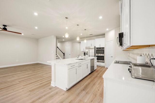 kitchen featuring white cabinetry, an island with sink, decorative light fixtures, and appliances with stainless steel finishes