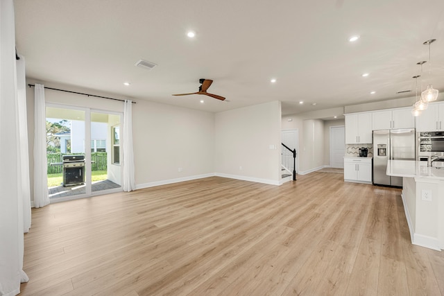 unfurnished living room with light wood-type flooring and ceiling fan