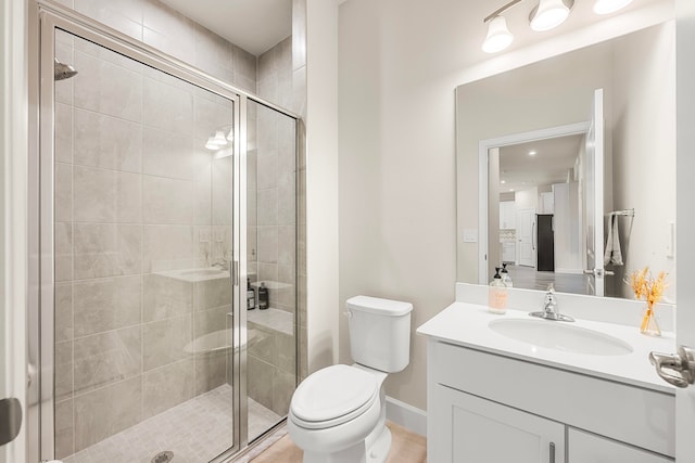 bathroom with vanity, toilet, and a shower with door