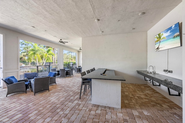 view of patio / terrace with ceiling fan, a wet bar, an outdoor hangout area, and an outdoor kitchen