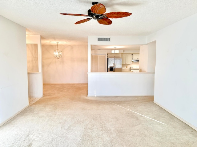 unfurnished living room featuring ceiling fan with notable chandelier, light colored carpet, and a textured ceiling