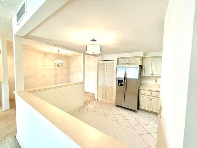 kitchen with stainless steel fridge with ice dispenser, a notable chandelier, pendant lighting, and light tile patterned flooring