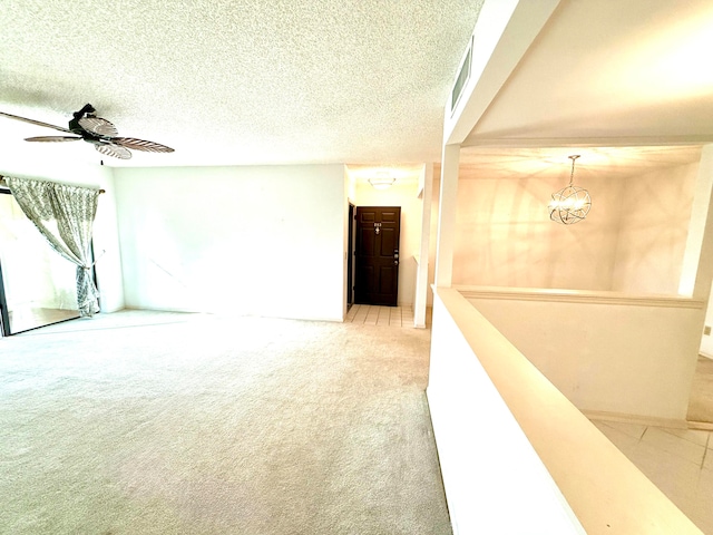 carpeted spare room featuring ceiling fan with notable chandelier and a textured ceiling