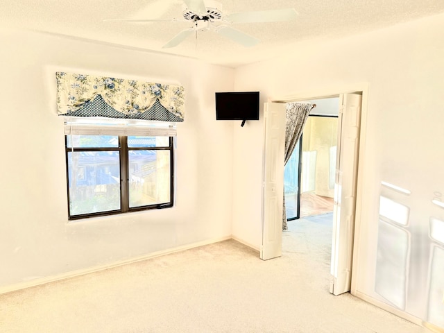 unfurnished room with carpet flooring, plenty of natural light, ceiling fan, and a textured ceiling