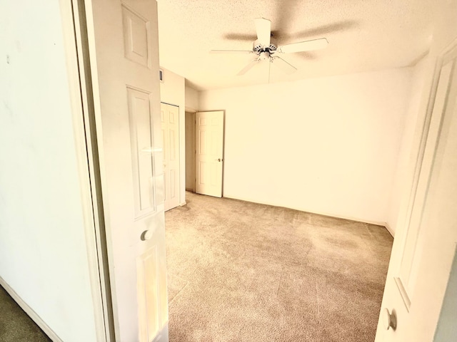 carpeted spare room featuring ceiling fan and a textured ceiling