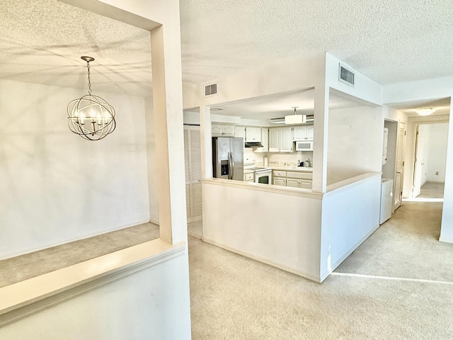 200 SE Four Winds Dr Unit 213, Stuart, FL 34996 - kitchen featuring white appliances, a chandelier, a textured ceiling, light colored carpet, and under cabinet range hood