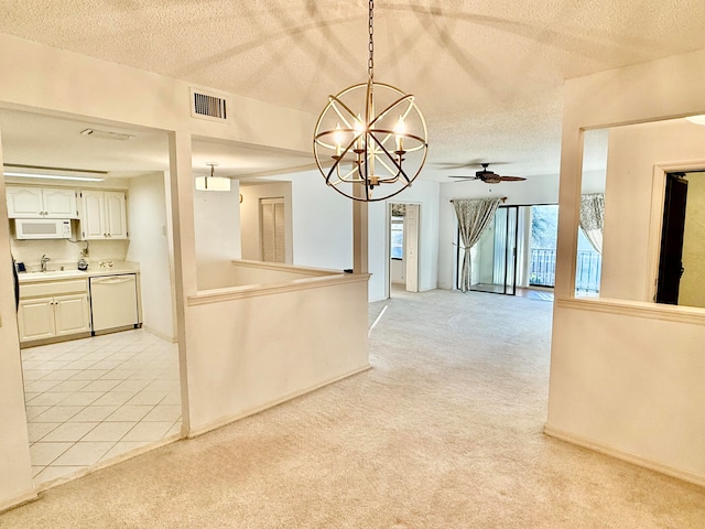 unfurnished dining area with light carpet, sink, ceiling fan with notable chandelier, and a textured ceiling