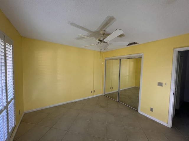 unfurnished bedroom with baseboards, visible vents, ceiling fan, a textured ceiling, and a closet