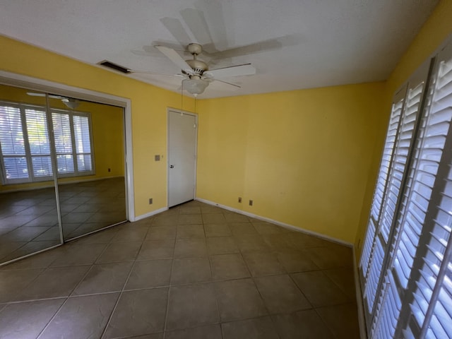 unfurnished bedroom with tile patterned flooring, visible vents, ceiling fan, and baseboards