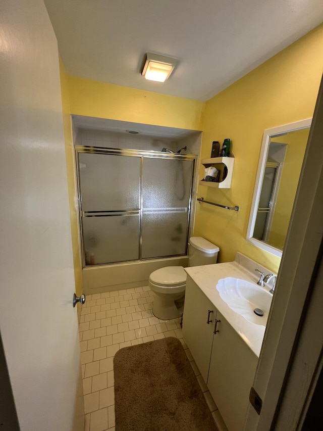 bathroom with tile patterned flooring, enclosed tub / shower combo, vanity, and toilet