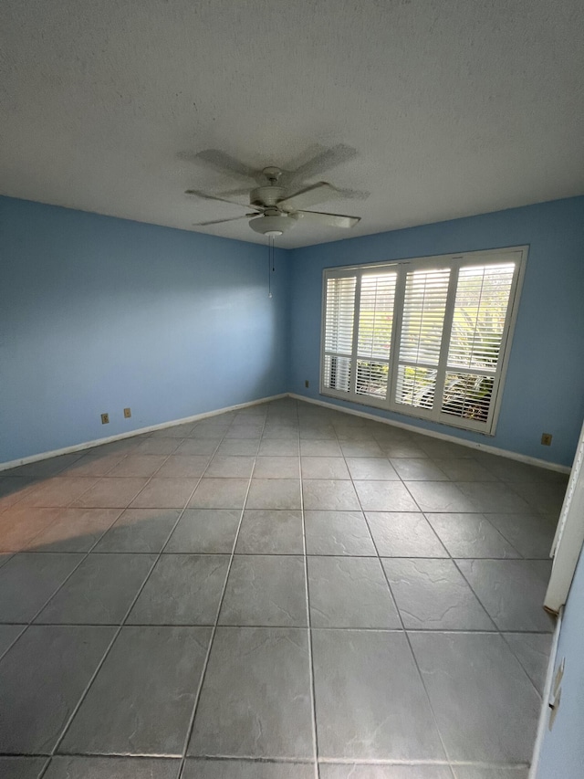 tiled empty room featuring ceiling fan and a textured ceiling