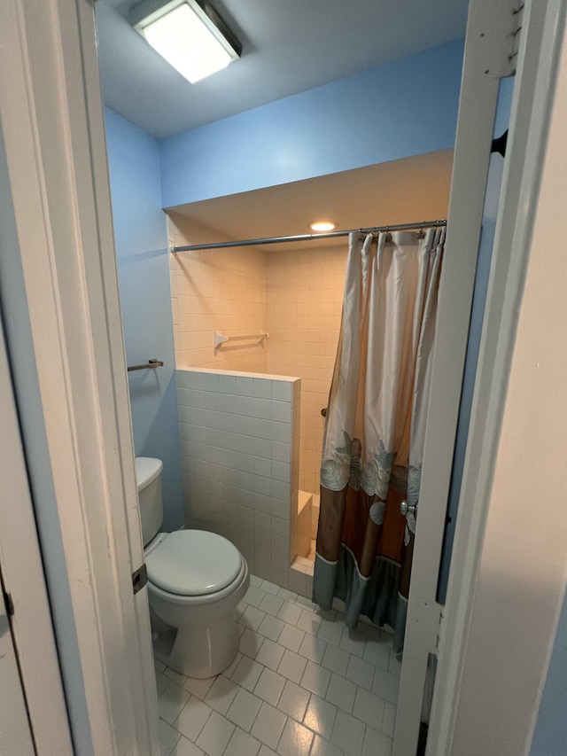 full bathroom with tile patterned flooring, a shower stall, toilet, and tile walls