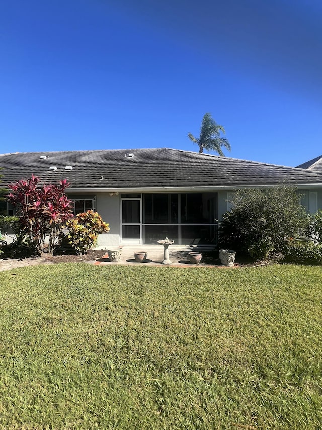 back of property with a sunroom and a lawn