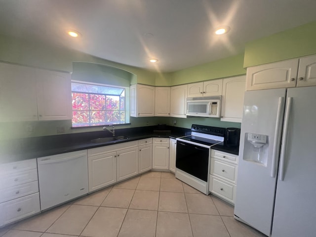 kitchen featuring dark countertops, white appliances, white cabinetry, and a sink