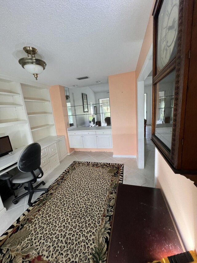 office space with ceiling fan, light tile patterned flooring, built in desk, and a textured ceiling