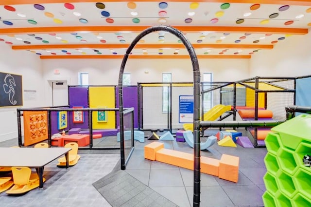 recreation room featuring beamed ceiling, a healthy amount of sunlight, and a towering ceiling